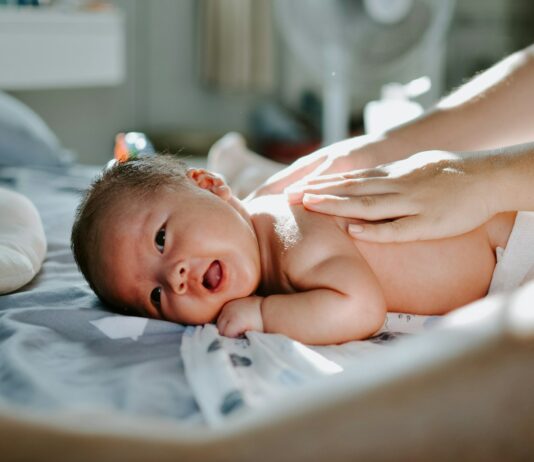 여름철 운동 후 피로 회복을 위한 마사지 팁 baby laying on bed while woman massaging his back
