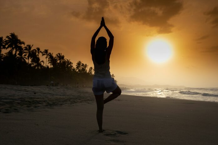 Photo by Olimpo Salazar woman in white tank top and white shorts standing on beach during sunset