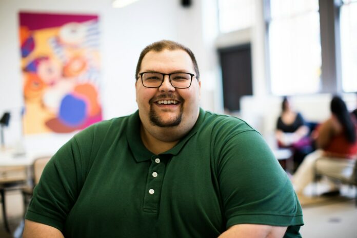 Photo by AllGo - An App For Plus Size People man sitting down wearing green polo shirt
