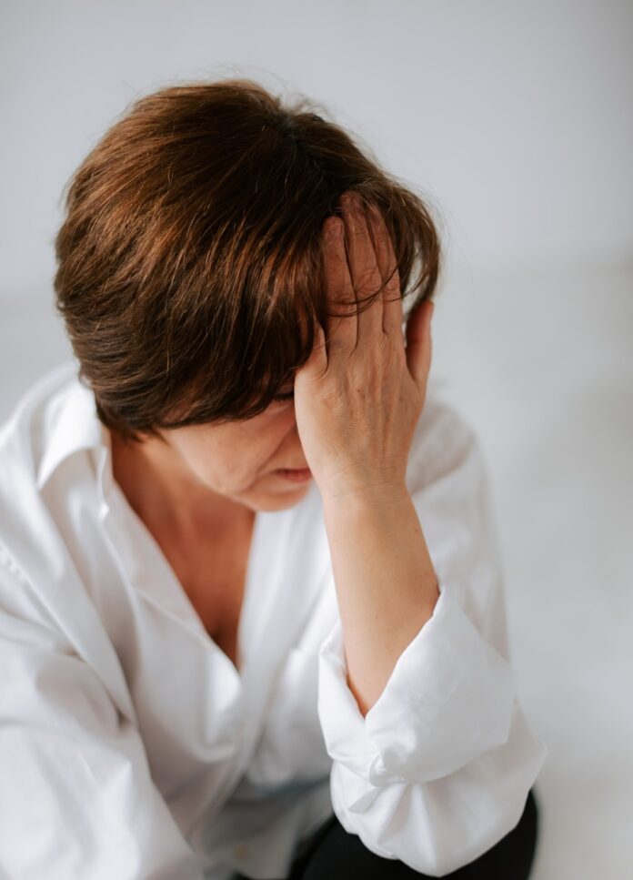 a woman sitting on a bed holding her head in her hands