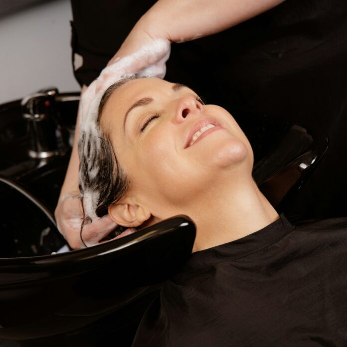 A woman enjoys a hair wash at a salon.