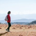 일상의 ‘걷기 습관’이 바꾸는 건강 트렌드…실천 루틴으로 만드는 방법 a man with a backpack walking across a dry grass covered field