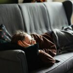 “끊이지 않는 피로, 나만의 루틴 찾기가 핵심” woman in pink jacket lying on gray couch